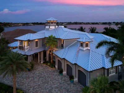 This Jupiter waterfront estate is protected by a custom standing seam metal roof, engineered to withstand Florida hurricanes while boosting curb appeal. Trust Alliance Group for your luxury roofing needs. Light blue standing seam metal roof on a luxury waterfront home in Jupiter, FL, installed by Alliance Group Roofing.